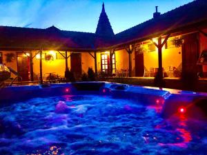 a hot tub in front of a house at night at Toscana Panzió in Zalacsány