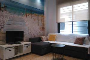 uma sala de estar com um sofá branco e uma televisão em SUITE JINETES em Málaga