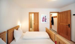 1 dormitorio con cama blanca y puerta de madera en Almrausch Apartments, en Sesto