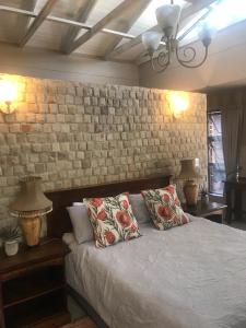 a bedroom with a bed with two pillows and a brick wall at Langebaan Golf Studio A1 - Langebaan Golf Estate in Langebaan