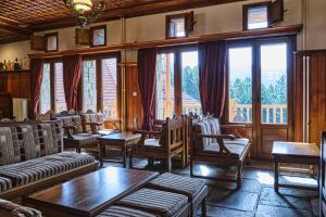 a living room with couches and tables and windows at Hotel Victoria in Metsovo