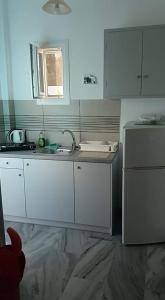 a kitchen with white cabinets and a sink and a refrigerator at Nefeli in Drios