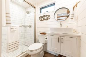 a bathroom with a toilet and a sink and a mirror at Deer Creek Tiny Container Home-12 Min to Magnolia in Bellmead