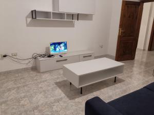 ein Wohnzimmer mit einem weißen Tisch und einem TV in der Unterkunft Appartamento Mare Sardegna Siniscola a 6 km da La Caletta Santa Lucia Capo Comino Berchida in Siniscola