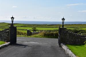 an open gate to a road with the ocean in the background at Aran View Holiday Homes Doolin - The Atlantic Stone House - Ocean Views in Doolin