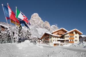 two flags in the snow in front of a lodge at B&B Bracun in Corvara in Badia