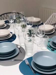 una mesa con platos blancos y vasos. en L Euphorie - Maison de ville de caractère 7 minutes de la mer - Le Treport - Mers les Bains, en Eu