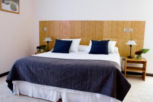 a bedroom with a large bed with blue pillows at Open Hotel in Quillota