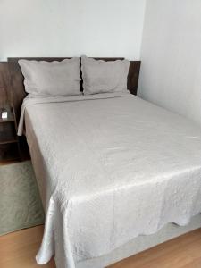 a bed with white sheets and pillows in a room at Plaza Fraga Maia in Feira de Santana +10 photos