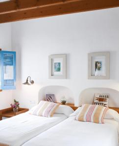 2 camas en un dormitorio con paredes blancas y techos de madera en Can Xicu Castello, en Sant Ferran de Ses Roques
