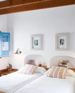 two beds in a bedroom with white walls and wooden ceilings at Can Xicu Castello in San Ferrán de ses Roques