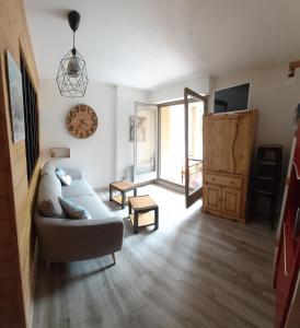 ein Wohnzimmer mit einer Couch und einer Uhr an der Wand in der Unterkunft Appartement 4 personnes Serre Chevalier Montagne/Contemporain Refait à neuf in La Salle Les Alpes