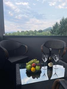 a table with a bowl of fruit and wine glasses at Ammirevole Ravne Apartments in Visoko