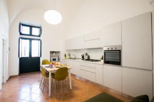 una cocina con armarios blancos y una mesa con sillas. en Giulia's House, en Galatina
