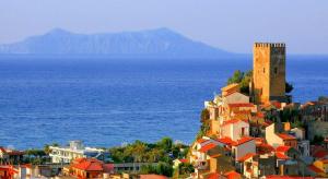 a town with a tower on a hill next to the ocean at Residence Il Vicoletto in Brolo