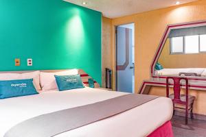 een slaapkamer met een groot bed met een groene muur bij Ayenda Frida Costa Azul in Mexico-Stad