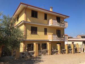 a yellow building with a balcony on the side of it at Casa vacanze al parco in Giba