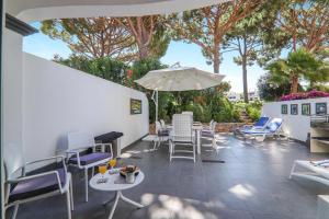 a patio with chairs and tables and an umbrella at Villa Karon in Almancil
