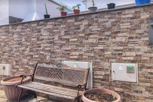 a bench sitting next to a brick wall with potted plants at LA CASITA DE BARTOLO in San Bartolomé