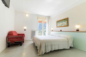 a white bedroom with a bed and a red chair at Aktiv Hotel Eden in Dro