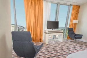 a hotel room with a television and a desk and chairs at Radisson Blu Hotel Batumi in Batumi