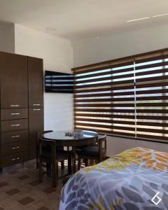1 dormitorio con mesa, cama, mesa y sillas en Departamentos Bonsai, en Torreón