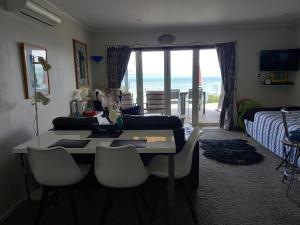 a living room with a table and a couch and a bed at The Fish and Jandal in Whangarei Heads