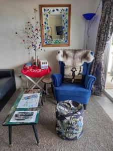 a living room with a blue chair and a table at The Fish and Jandal in Whangarei Heads