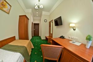 a hotel room with a bed and a desk at Milyutinsky Hotel in Cherepovets