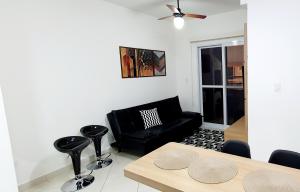 een woonkamer met een zwarte bank en een tafel bij Apartamento 2 Novíssimo e Bem Localizado - Itaguá - UBATUBA-SP in Ubatuba