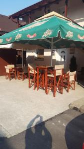 a group of wooden tables and chairs under a green umbrella at Rooms Sejo in Kolašin