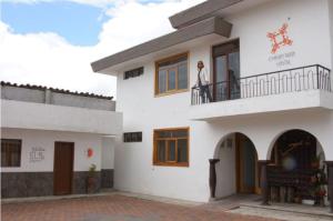 una donna sul balcone di un edificio bianco di Hotel Chasky Cuenca a Cuenca