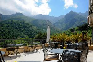 a patio with tables and chairs with mountains in the background at Cas'Anna Lidia - Hôtel De Charme in Feliceto