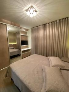 a bedroom with a large bed and a mirror at Apartamento em Gramado com piscina in Gramado