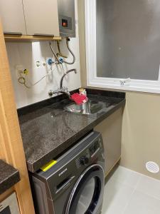 a kitchen with a washing machine and a sink at Apartamento em Gramado com piscina in Gramado +14 photos