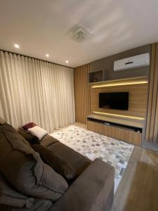 a living room with a couch and a television at Apartamento em Gramado com piscina in Gramado