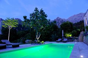 a swimming pool in a backyard with mountains in the background at Cas'Anna Lidia - Hôtel De Charme in Feliceto