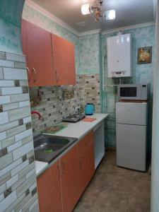 eine kleine Küche mit orangefarbenen Schränken und einem weißen Kühlschrank in der Unterkunft 1 комнатная квартира в центре Мукачева, улица Мира in Mukatschewo