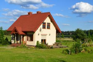 a house with a red roof on a green field at Zagajnik Holiday House in Sucha Rzeczka