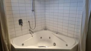 a bath tub in a tiled bathroom with a shower at 23a Leamington Street in Hanmer Springs +24 photos