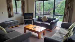 a living room with couches and a tv and a table at 23a Leamington Street in Hanmer Springs