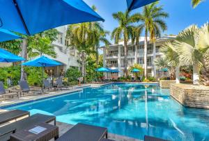 basen z niebieskimi parasolami i palmami w obiekcie Elysium The Beach Club w mieście Palm Cove