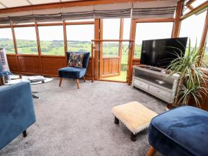 a living room with a tv and chairs and windows at The Thyme House in Keighley