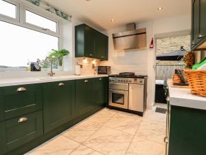 a kitchen with green cabinets and a stove at The Thyme House in Keighley
