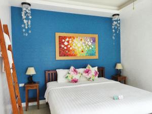 een slaapkamer met een blauwe muur en een bed met kussens bij The Snug Airportel - Phuket Airport in Nai Yang Beach