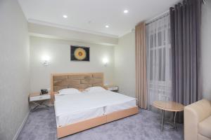 a bedroom with a bed and a table and a chair at Reikartz Amirun Tashkent in Tashkent
