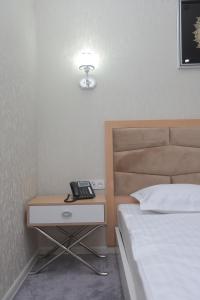 a bedroom with a bed and a phone on a night stand at Reikartz Amirun Tashkent in Tashkent