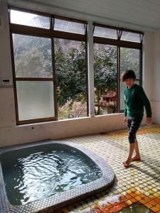 un jeune garçon debout en face d'une piscine dans l'établissement ペット可 Akiu-Canada 鴻ノ巣温泉, à Sendai