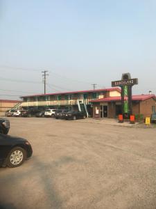 een tankstation met auto's geparkeerd op een parkeerplaats bij RANCHLAND Inn in Nanton