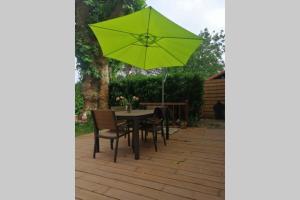 una mesa y sillas con una sombrilla verde en el patio en L'antre de l'artiste - Calme & Nature -maisonnette confort, en Bénesse-Maremne